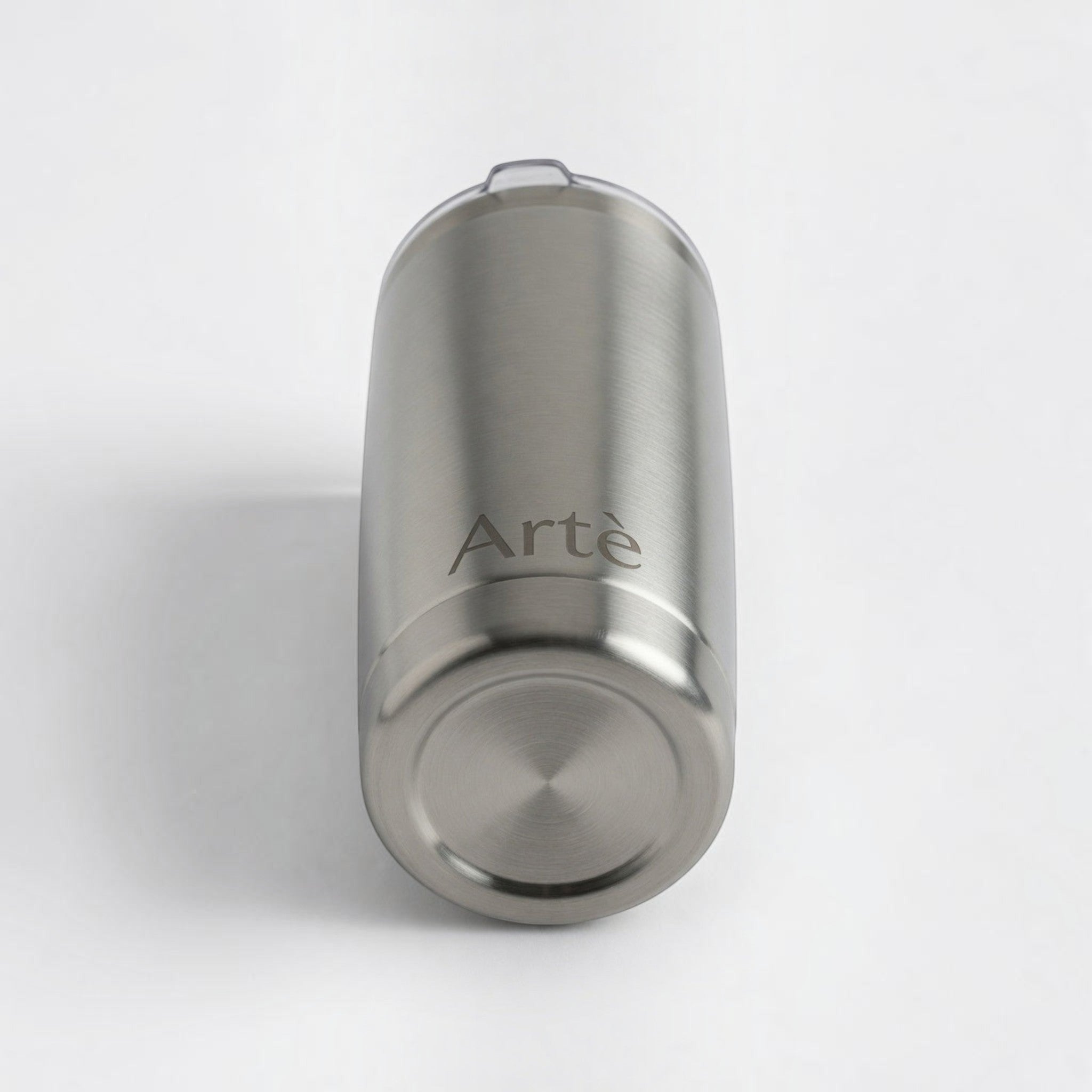 ArtèCup 20oz stainless steel tumbler with a brushed metal finish and clear lid, viewed from the bottom angle.